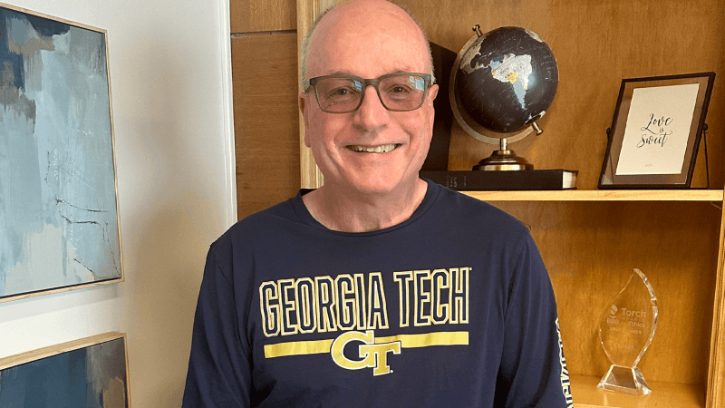 Man with glasses and a blue shirt smiling at the camera